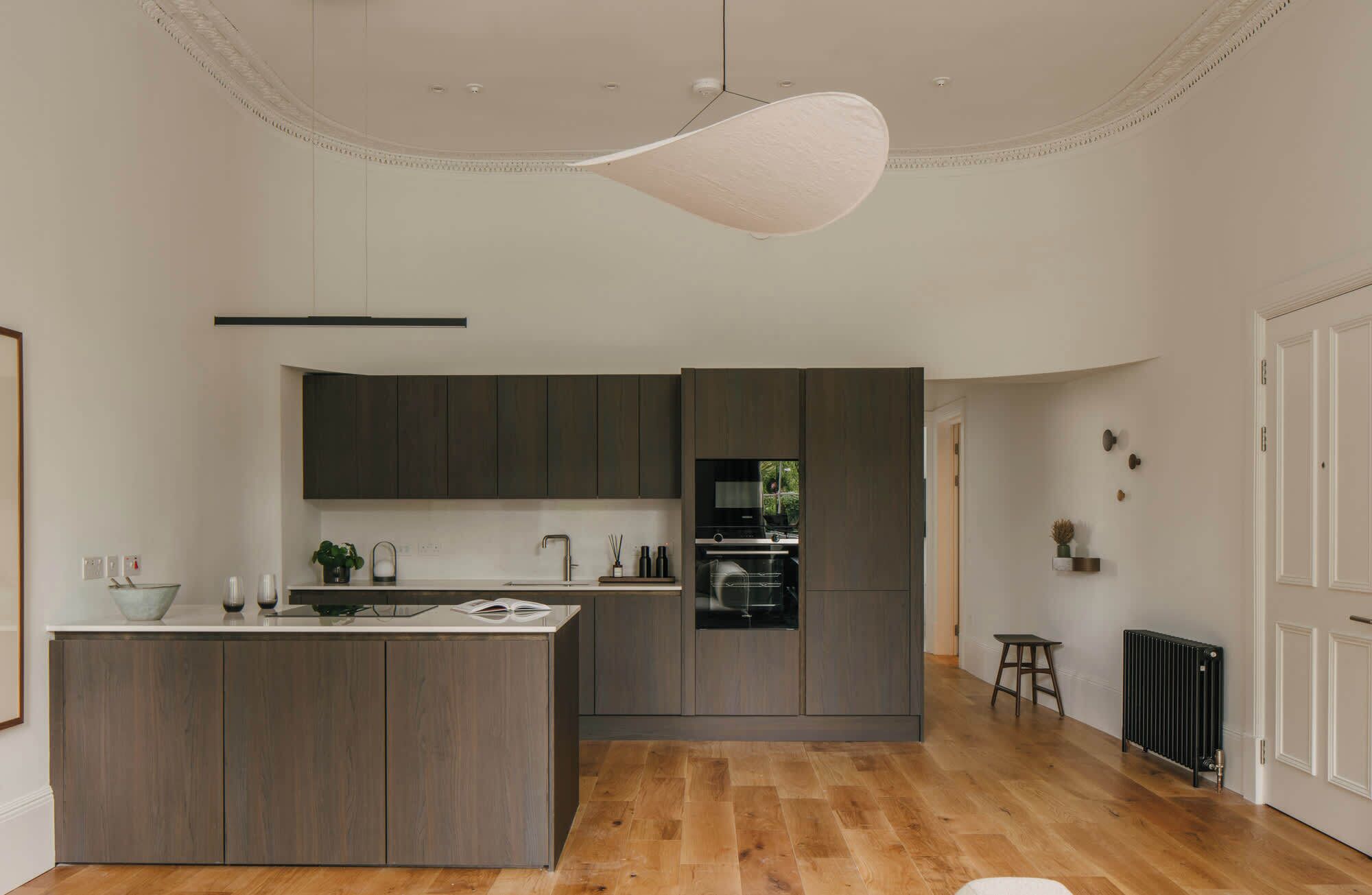 A modern kitchen with dark wood cabinets, a central island, and a built-in oven.