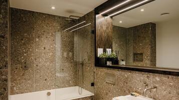 A modern bathroom with a glass-enclosed shower, a white toilet, and a white sink with a mirror above.