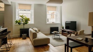 Una sala de estar moderna con un sofá, una mesa de comedor, un televisor y un ventanal grande.