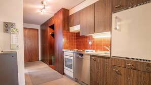 A modern kitchen with wooden cabinets, a built-in oven, and a stainless steel dishwasher. - Rothornblick 39 by Arosa Holiday Appartement/Fewo,   4-Bettwohnung by Interhome (Arosa)