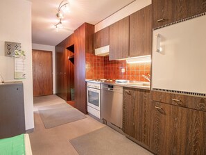 A modern kitchen with wooden cabinets, a built-in oven, and a stainless steel dishwasher.
