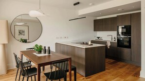 Een moderne keuken met een centraal eiland, houten vloeren en donkere keukenkastjes.