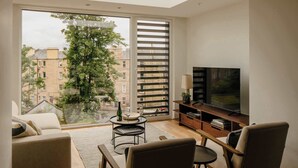 Een moderne woonkamer met een groot raam, een flatscreen televisie en een gezellige zithoek.