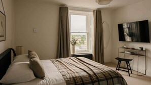 A bedroom with a bed, a desk, a TV, and a window with curtains. - Urban Apartment in Claremont Residences (Edinburgh)