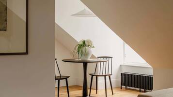 A modern loft with a dining area featuring a round table, two chairs, and a potted plant.