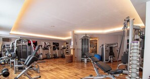A gym with various exercise equipment, a wooden floor, and a wall-mounted TV. - Rothornblick 50 by Arosa Holiday Appartement/Fewo, Badewanne, 6-Bettwohnung by Interhome (Arosa)