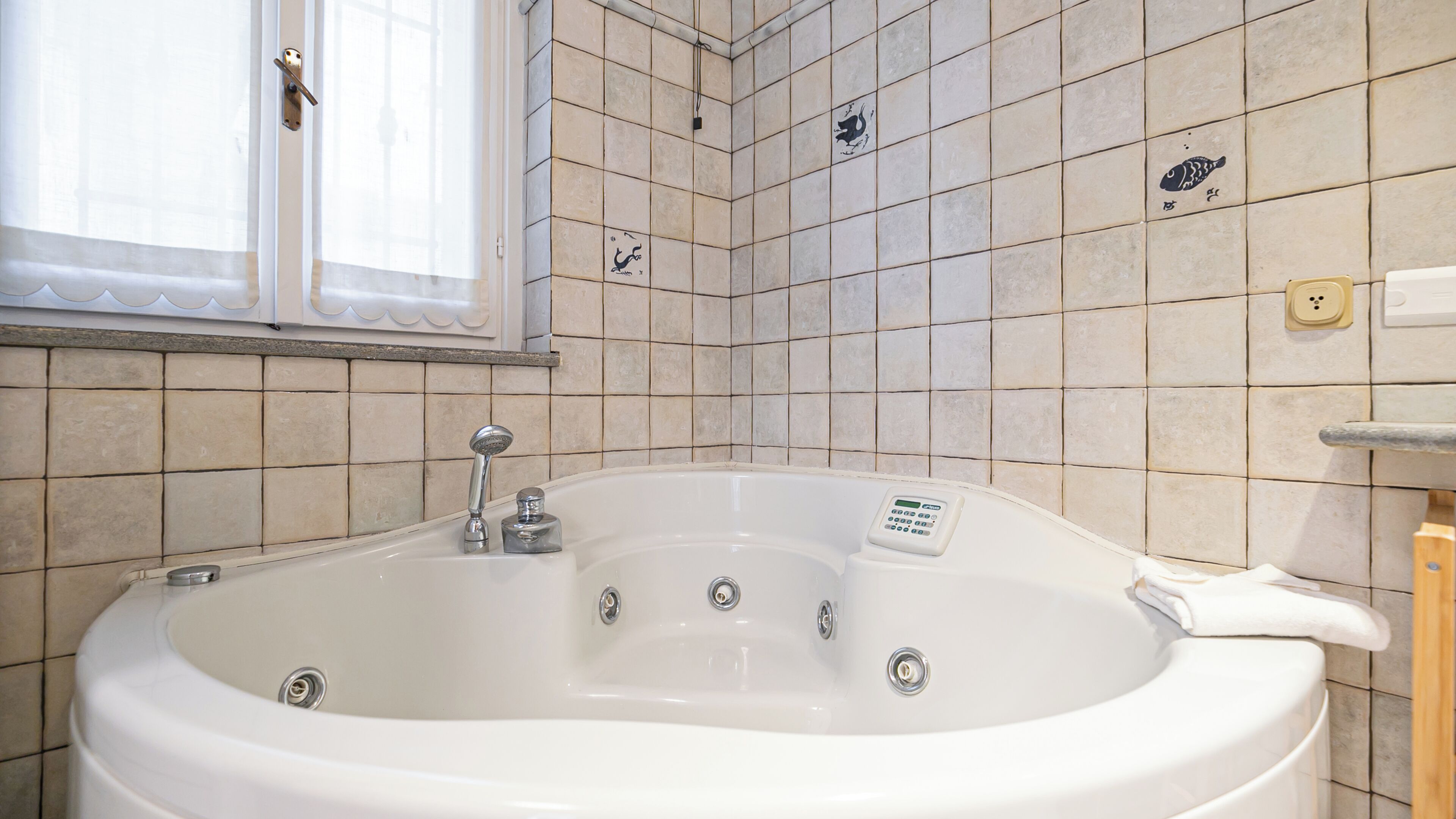 Une salle de bain avec une grande baignoire, une fenêtre et des murs carrelés.