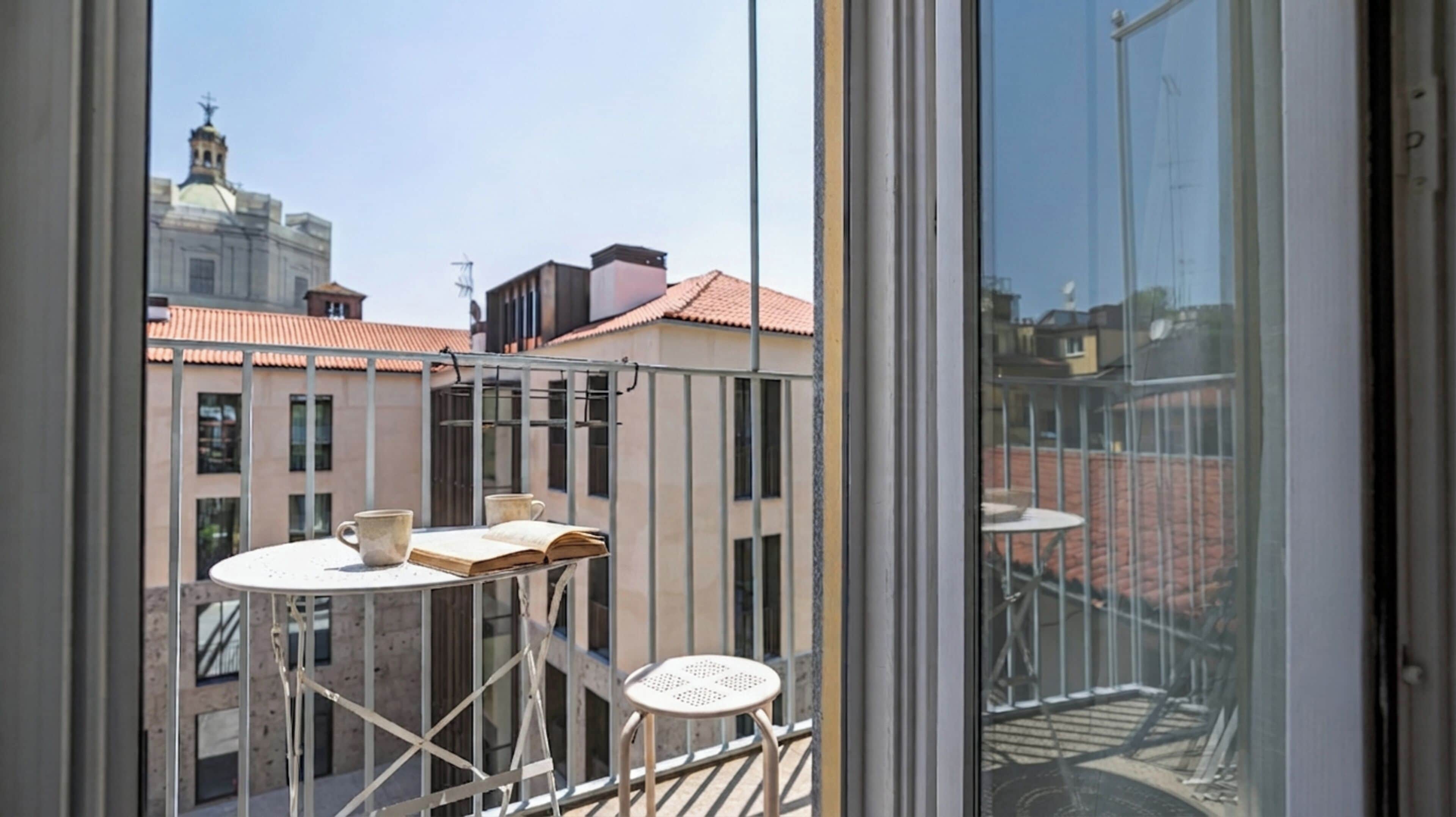 A balcony with a table, two chairs, and a book.