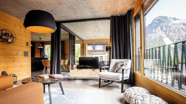 A modern interior with a wooden ceiling, a dining area, a TV, and a large window with a mountain view. - Haus Burgermeister Wohnung Älplihorn Appartement/Fewo, Dusche oder Bad, WC, 4-Be by Interhome (Arosa)
