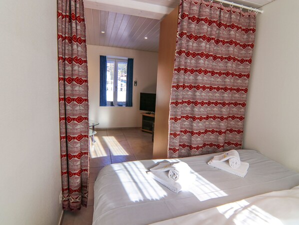 Een hotelkamer met een bed, een televisie en een raam met gordijnen.