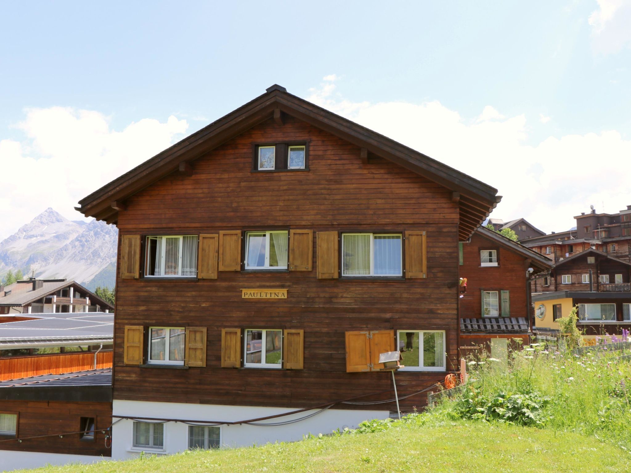 A multi-story wooden building with a sign reading 'PAULTINA' and a mountain in the background.