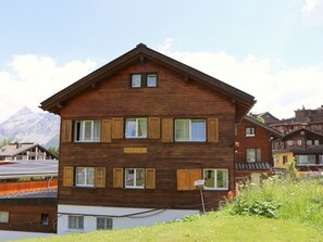 Ein mehrstöckiges Holzhaus mit dem Schild 'PAULTINA' und einem Berg im Hintergrund.
