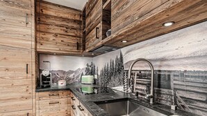 A kitchen with wooden cabinets, a stainless steel sink, and a mountain-themed wall mural. - Alpslodge Amelia Appartement/Fewo, Bad, WC, Terrasse by Interhome (Arosa)
