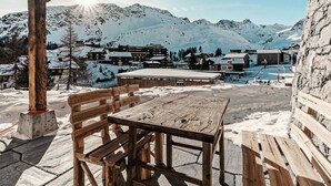 A wooden table and chairs under a wooden structure with a view of snow-covered mountains and buildings. - Alpslodge Amelia Appartement/Fewo, Bad, WC, Terrasse by Interhome (Arosa)