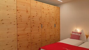 Ein Schlafzimmer mit einem Holfischschrank, einem Bett mit weißer Bettwäsche und einer roten Decke sowie einem Nachttisch mit einer Lampe.