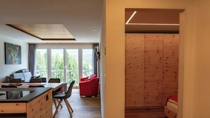 Ein modernes Interieur mit einer Essecke, einem roten Sessel und einem Holzschrank.