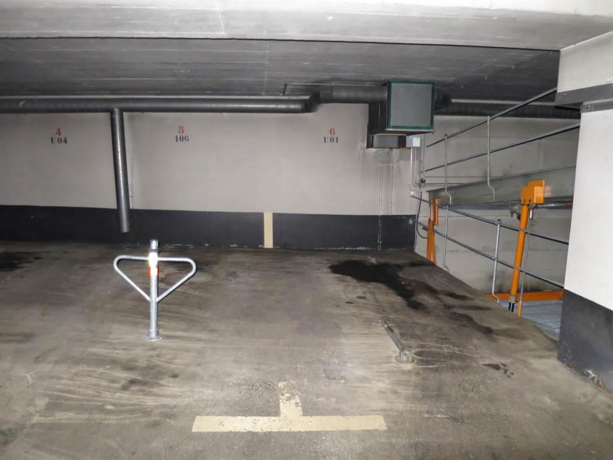 A parking garage with concrete floors, metal railings, and a few scattered objects.