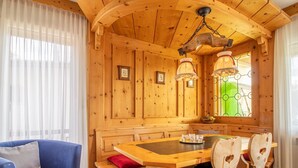 A wooden interior with a dining table, chairs, a sofa, and a window with a green view. - Villa Franca U01 Appartement/Fewo,   Villa Franca UO1 by Interhome (Arosa)