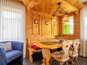 A wooden interior with a dining table, chairs, a sofa, and a window with a green view. - Villa Franca U01 Appartement/Fewo,   Villa Franca UO1 by Interhome (Arosa)