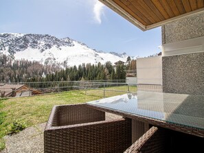 A modern outdoor seating area with a glass table and wicker chairs, overlooking a mountainous landscape. - Villa Franca U01 Appartement/Fewo,   Villa Franca UO1 by Interhome (Arosa)