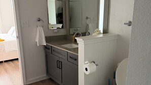 Ein Badezimmer mit Toilette, Waschbecken, Spiegel und Handtuchhalter.