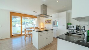 A modern kitchen with a central island, built-in appliances, and a dining area with a view. - Sunnaschy Heidi by Arosa Vacations Appartement/Fewo, Dusche und Badewanne, 2 Sch by Interhome (Arosa)