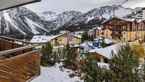 Un village de montagne aux maisons en bois, aux toits couverts de neige, et qui offre une vue sur des montagnes aux sommets enneigés.