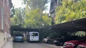 Een smalle steeg met geparkeerde auto's en een witte bestelwagen, alles overdekt.