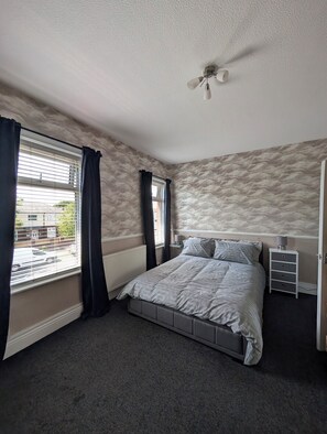 A bedroom with a bed, a ceiling fan, a nightstand, and a window with curtains. - Seaside Retreat - Golf Coast & Holiday Home  (Southport)