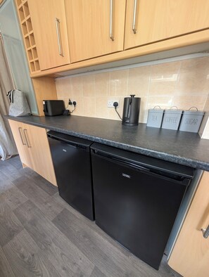 A kitchen with wooden cabinets, a black dishwasher, a coffee maker, and labeled containers for tea, coffee, and sugar. - Seaside Retreat - Golf Coast & Holiday Home  (Southport)