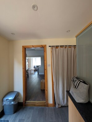 A room with a wooden door leading to a dining area, a grey trash bin, and a grey bag on a black countertop. - Seaside Retreat - Golf Coast & Holiday Home  (Southport)