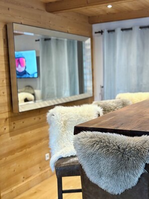 Un interior de madera con un espejo grande, almohadones de piel y un televisor.