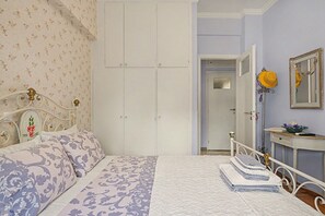 Ein Schlafzimmer mit einem Bett, einem Kleiderschrank, einem Spiegel und einem Nachttisch mit Handtüchern.