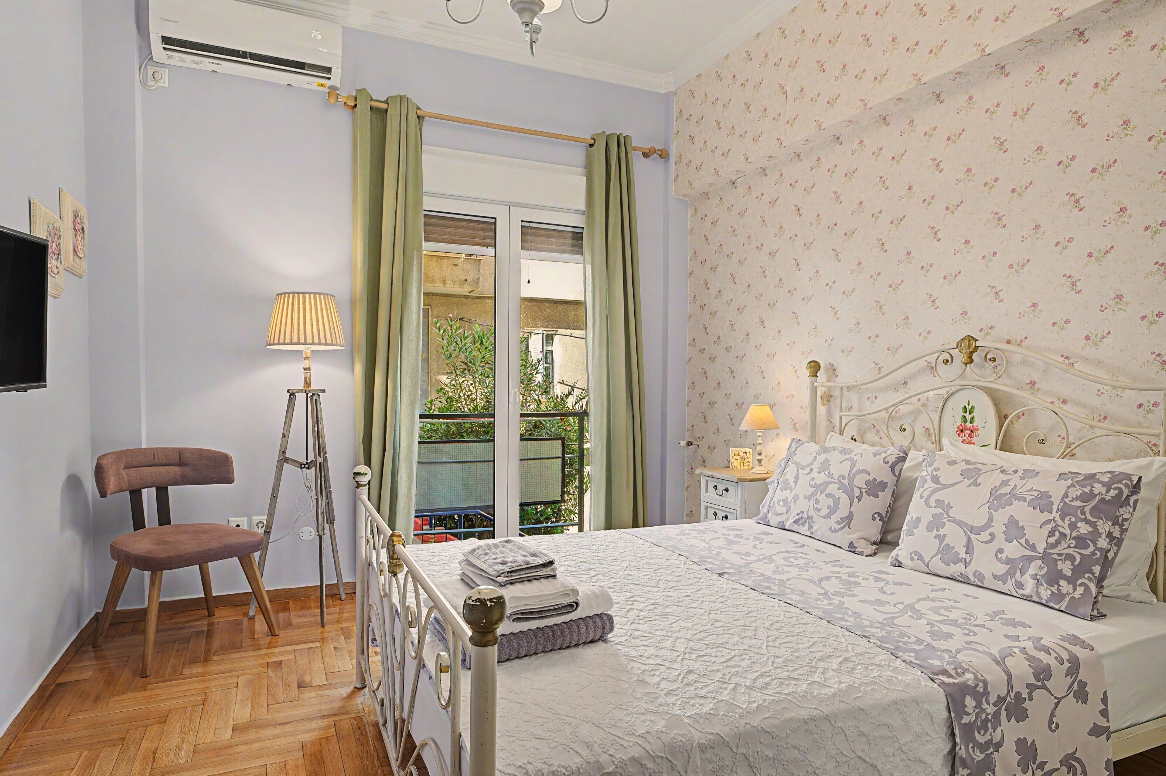 A bedroom with a bed, a chair, a floor lamp, and a window with curtains.