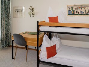 Ein Stockbett mit Schreibtisch und Stuhl, ein gerahmtes Bild an der Wand und eine Wanddekoration.