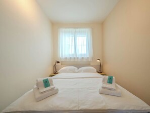 A hotel room with a bed, two bedside lamps, a window with curtains, and two towels on the bed. - Viktoria B33 by Arosa Vacations Appartement/Fewo, Dusche und Bad, WC, 2 Schlafrä by Interhome (Arosa)