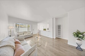 Un salon moderne avec un canapé, une petite table d’appoint ronde et une plante en pot.