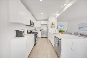 Une cuisine moderne avec des meubles blancs, un îlot central et un réfrigérateur.