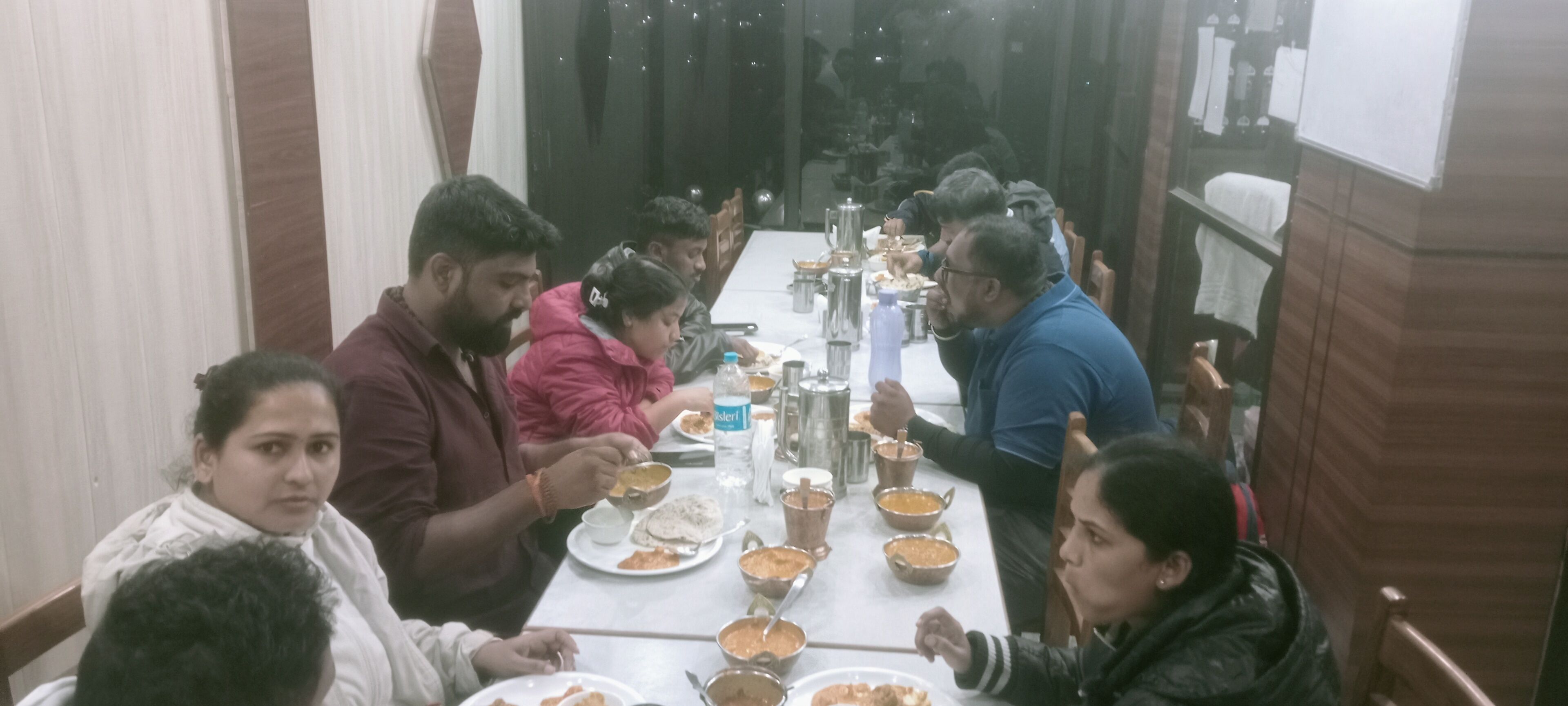 Un grupo de personas comiendo en una mesa con diferentes platos y cubiertos.