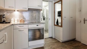Eine moderne Küche mit weißen Schränken, einem eingebauten Ofen und einer Arbeitsplatte aus Granit.
