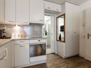A modern kitchen with white cabinetry, a built-in oven, and a granite countertop. - Haus Lorez B-5 Appartement/Fewo, Dusche oder Bad, WC, 2-Bettwohnung by Interhome (Arosa)