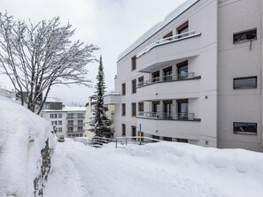 A multi-story building with balconies, a snow-covered ground, and a clear sky. - Haus Lorez B-5 Appartement/Fewo, Dusche oder Bad, WC, 2-Bettwohnung by Interhome (Arosa)