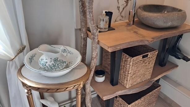 A room with a decorative table, a bowl, a bottle, and wicker baskets. - Bed and Breakfast 'La Chambre JP À "Parenthèse"' with Mountain View, Shared Garden and Wi-Fi (Folles)