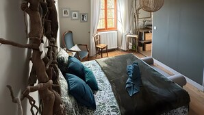 A bedroom with a bed, a chair, a table, and a large decorative branch. - Bed and Breakfast 'La Chambre JP À "Parenthèse"' with Mountain View, Shared Garden and Wi-Fi (Folles)