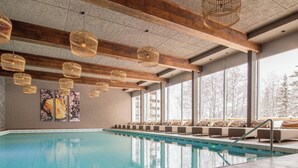 An indoor swimming pool with wooden beams, wicker pendant lights, and a seating area with cushions. - Rothornblick 25 by Arosa Holiday Appartement/Fewo, Bad, WC, 4-Bettwohnung by Interhome (Arosa)