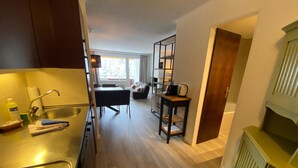 A modern kitchen with a built-in stove, a sink, and a dining area with a table and chairs. - Rothornblick 25 by Arosa Holiday Appartement/Fewo, Bad, WC, 4-Bettwohnung by Interhome (Arosa)