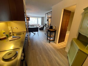 A modern kitchen with a built-in stove, a sink, and a dining area with a table and chairs. - Rothornblick 25 by Arosa Holiday Appartement/Fewo, Bad, WC, 4-Bettwohnung by Interhome (Arosa)
