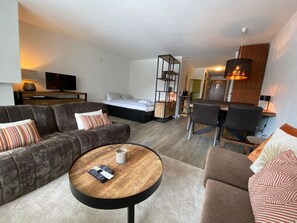 Ein modernes Wohnzimmer mit einer Couch, einem Couchtisch und einem Fernseher.