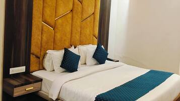 A bedroom with a tufted headboard, a bed with white and teal bedding, a wooden nightstand, a ceiling fan, and an air conditioning unit.
