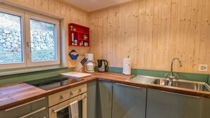Eine kompakte Küche mit Holzwänden, einem Einbauofen, einem Spülbecken und einem Fenster mit Blick auf eine Steinwand.